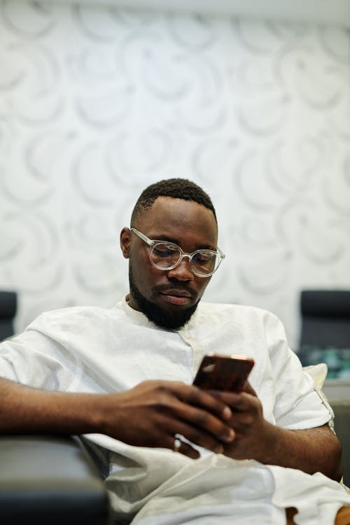 Close-Up Shot of a Man in White Button-Up Shirt Using His Smartphone