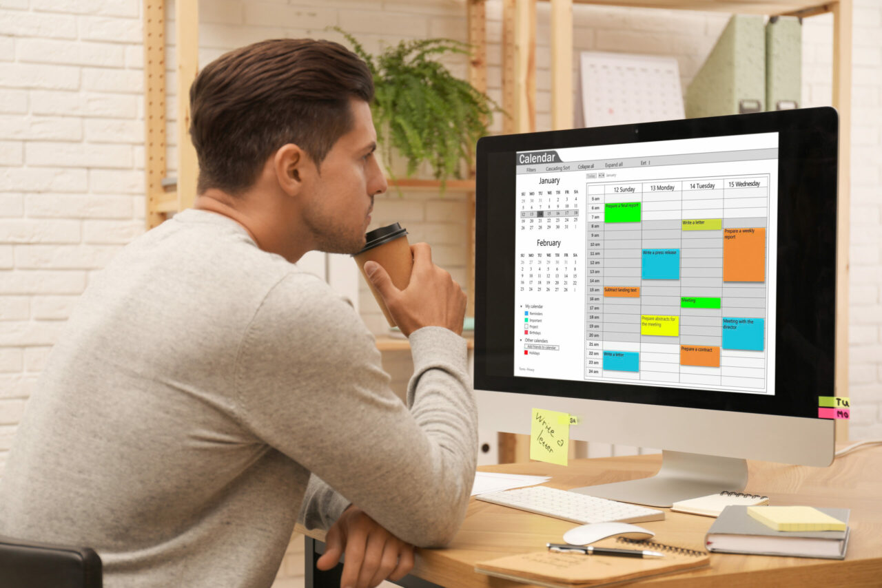 Handsome man using calendar app on computer in office